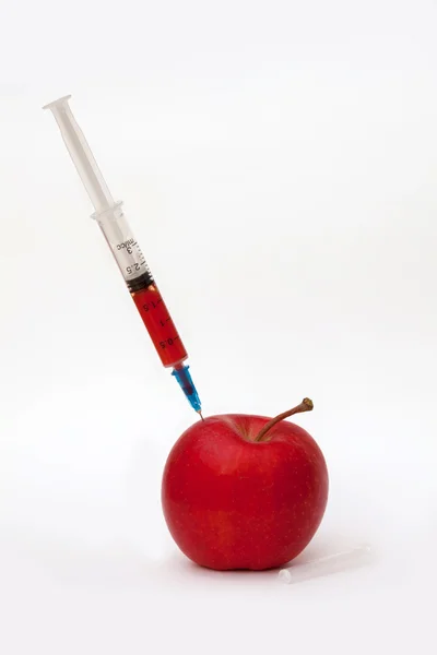 Красное яблоко и медицинский шприц — стоковое фото