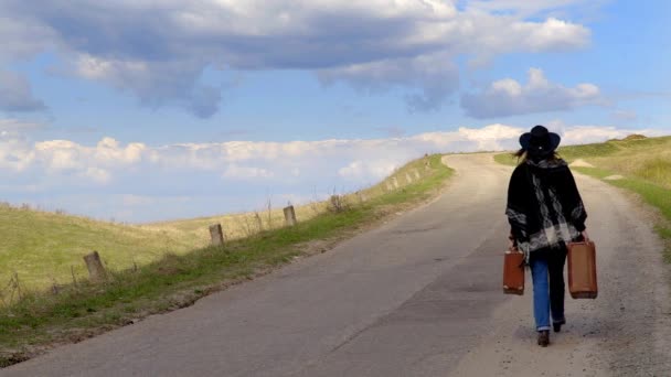 Těhotná dívka chůze po silnici s dvěma starými kufry na trávě v létě — Stock video