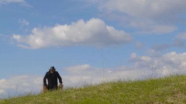 İki eski çanta ile yol boyunca yaz aylarında çim üzerinde yürüyen adam