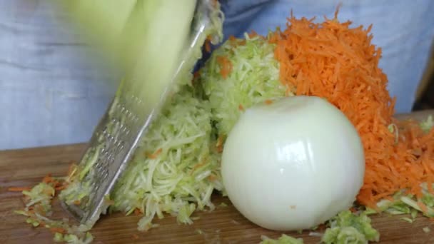 Zucchini, Möhren und Zwiebeln auf einer Reibe hacken — Stockvideo