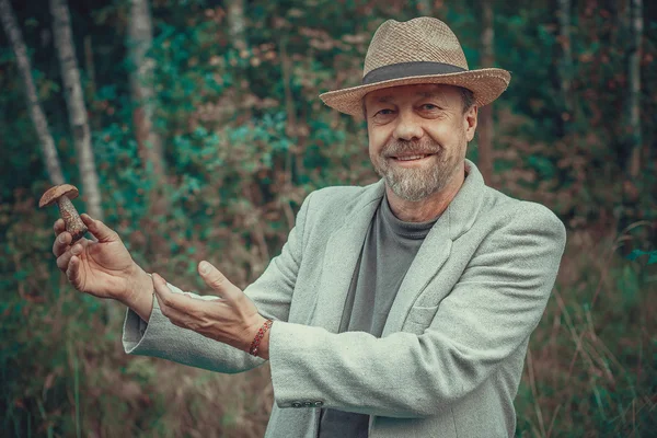 Een man in een hoed met een paddestoel in zijn hand — Stockfoto