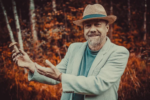 Een man in een hoed met een paddestoel in zijn hand — Stockfoto