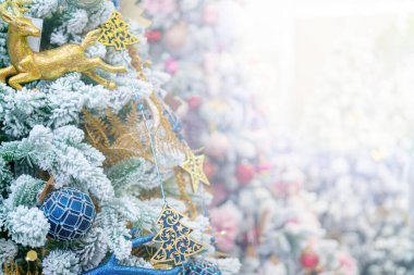 Beyaz karla kaplı ağaç oyuncaklarla süslenmiş..