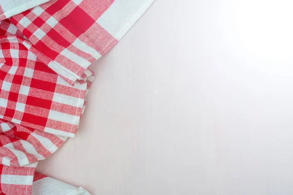 Red checkered towel on the kitchen table. Wooden table background.