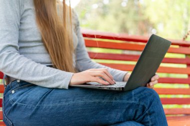 Kız kucağında bir dizüstü bilgisayar tutuyor. Açık hava işi.. 