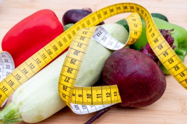 Tahta kesme tahtasındaki sarı mezura ve sebzeler. Sağlıklı yaşam tarzı diyeti. 