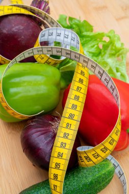 Tahta kesme tahtasındaki sarı mezura ve sebzeler. Sağlıklı yaşam tarzı diyeti. 