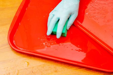 Fast food 'da kırmızı plastik yemek tepsisinin dezenfekte edilmesi. Tepsiyi sünger ve sabunla yıkıyorum.. 
