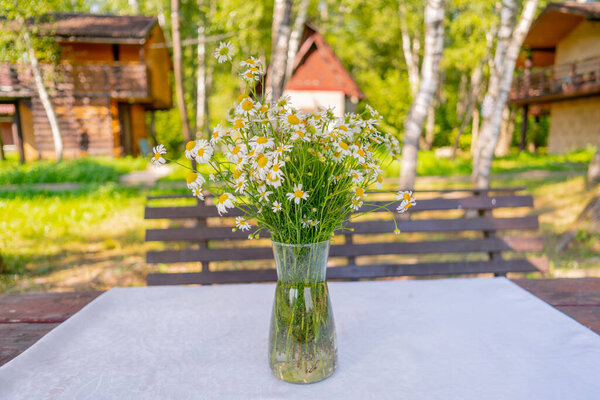 Букет полевых маргариток на столе в вазе. 