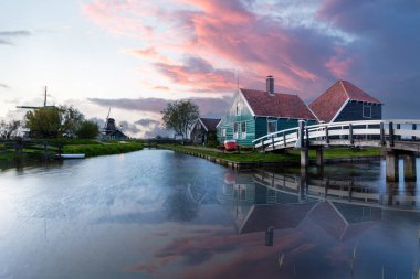 Zaanse Schans Hollanda geleneksel evler yel değirmenleri ve kanallar renkli bir günbatımını yansıtıyor.