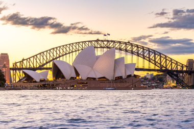 Sydney, 15 Ekim 2023: Turistler gün batımında ikonik Opera Binası ve Liman Köprüsü 'ne hayran kalırken, Köprü tırmanışçıları da görülüyor