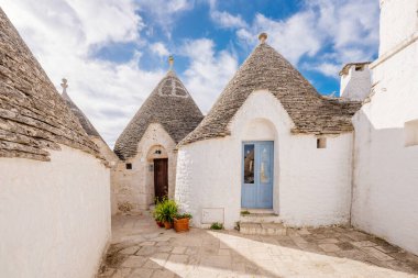 Alberobello, İtalya: Mavi gökyüzünün altında büyüleyici bir caddede tarihi Trulli evleri.