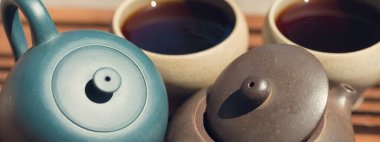 Çin çay seremonisi. Balçıktan yapılmış seramik çaydanlık ve ahşap bir arka planda kaseler.