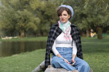 Parktaki genç kadın cep telefonuyla konuşuyor. Fransız tarzında şirin bir kız portresi..