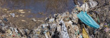 Çöp sahasında plastik torbalar ve şişeler. İzinsiz çöp salınımı, doğanın kirliliği. Çevre felaketi kavramı.