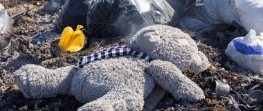 Oyuncak ayı çöp sahasının ortasına atılmış bir şekilde yatıyor. Çevre felaketi kavramı.