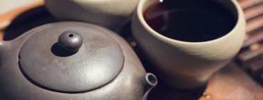 Çin çay seremonisi. Balçıktan yapılmış seramik çaydanlık ve ahşap bir arka planda kaseler.