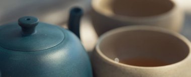 Çin çay seremonisi. Balçıktan yapılmış seramik çaydanlık ve ahşap bir arka planda kaseler.