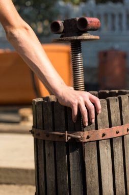 Kırmızılı şarap presi ve sarmal vida. Şarap üreticisinin elleri kapalı..