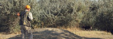 Tüfekli ördek avcısı çayırda yürüyor..