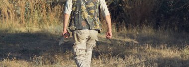 Tüfekli ördek avcısı çayırda yürüyor..