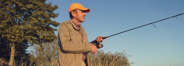 Nehir kenarında duran ve balık tutmaya çalışan bir balıkçı. Spor, eğlence, yaşam tarzı..