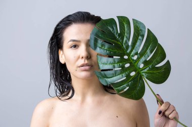 Doğal yeşil palmiye yaprağı portresi olan bir kadın. Moda, güzellik, makyaj, kozmetik.