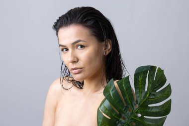 Doğal yeşil palmiye yaprağı portresi olan bir kadın. Moda, güzellik, makyaj, kozmetik.