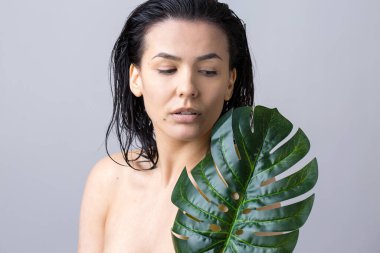 Doğal yeşil palmiye yaprağı portresi olan bir kadın. Moda, güzellik, makyaj, kozmetik.
