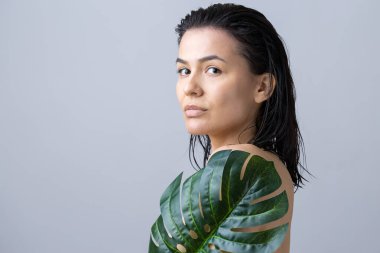 Doğal yeşil palmiye yaprağı portresi olan bir kadın. Moda, güzellik, makyaj, kozmetik.