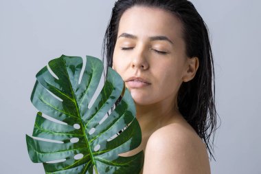Doğal yeşil palmiye yaprağı portresi olan bir kadın. Moda, güzellik, makyaj, kozmetik.