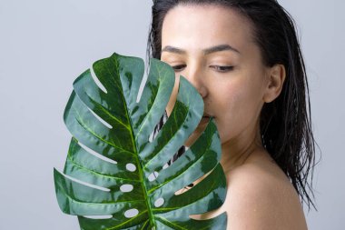 Doğal yeşil palmiye yaprağı portresi olan bir kadın. Moda, güzellik, makyaj, kozmetik.