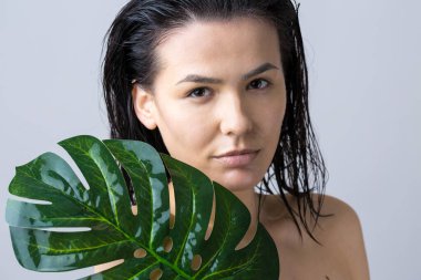 Doğal yeşil palmiye yaprağı portresi olan bir kadın. Moda, güzellik, makyaj, kozmetik.