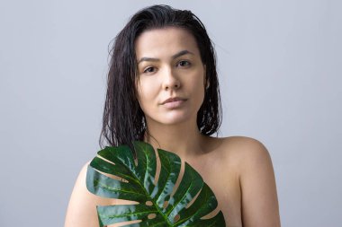 Doğal yeşil palmiye yaprağı portresi olan bir kadın. Moda, güzellik, makyaj, kozmetik.