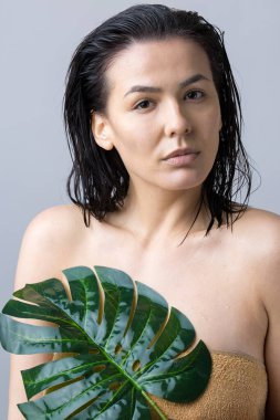 Doğal yeşil palmiye yaprağı portresi olan bir kadın. Moda, güzellik, makyaj, kozmetik.