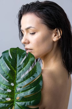 Doğal yeşil palmiye yaprağı portresi olan bir kadın. Moda, güzellik, makyaj, kozmetik.