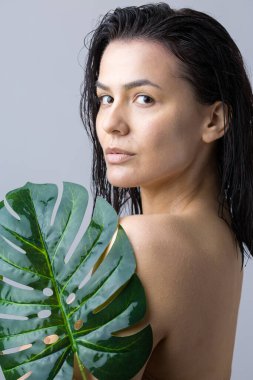 Doğal yeşil palmiye yaprağı portresi olan bir kadın. Moda, güzellik, makyaj, kozmetik.
