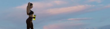 Gökyüzü arka planında spor kıyafetleriyle poz veren kadın. Vücudun orta kısmı..