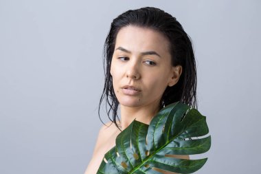 Doğal yeşil palmiye yaprağı portresi olan bir kadın. Moda, güzellik, makyaj, kozmetik.