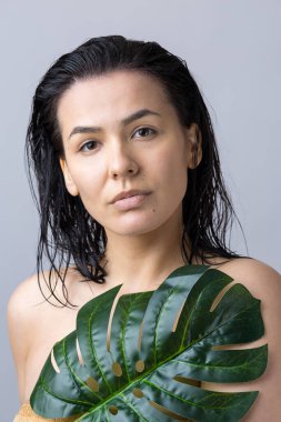 Doğal yeşil palmiye yaprağı portresi olan bir kadın. Moda, güzellik, makyaj, kozmetik.