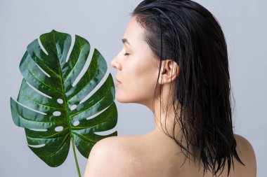 Doğal yeşil palmiye yaprağı portresi olan bir kadın. Moda, güzellik, makyaj, kozmetik.