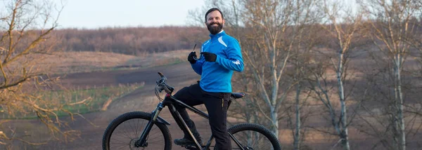 Cyclist in pants and fleece jacket on a modern carbon hardtail bike with an air suspension fork. The guy on the top of the hill rides a bike.