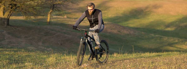 运动残忍的胡子家伙在现代山地自行车上 春天的青山上骑自行车 — 图库照片