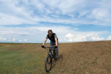 Modern dağ bisikletindeki vahşi sakallı adam. Gölün kenarındaki tuzlu bir yerde bir bisikletçi..