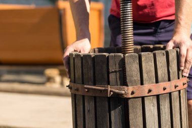 Kırmızılı şarap presi ve sarmal vida. Şarap üreticisinin elleri kapalı..