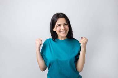 Çekici bağırışların yakın portresi. Genç yaşta yumruklarıyla gülümsüyor. Gri arka planda izole kot gömlek giyen kız arkadaşı.