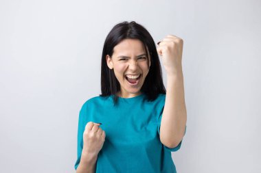 Çekici bağırışların yakın portresi. Genç yaşta yumruklarıyla gülümsüyor. Gri arka planda izole kot gömlek giyen kız arkadaşı.