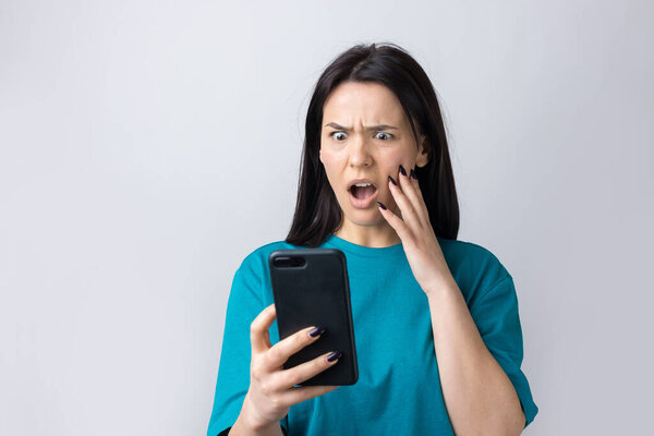 Front portrait of young smiling woman using mobile phone against grey background