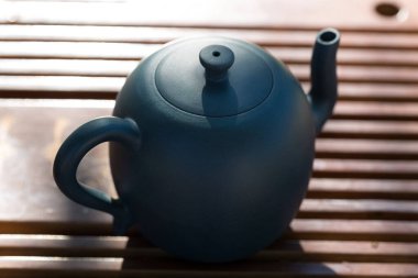 Çin çay seremonisi. Balçıktan yapılmış seramik çaydanlık ve ahşap bir arka planda kaseler.