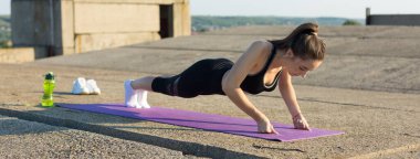 Spor giyimli genç, zayıf bir atletik kız bir takım egzersizler sergiliyor..